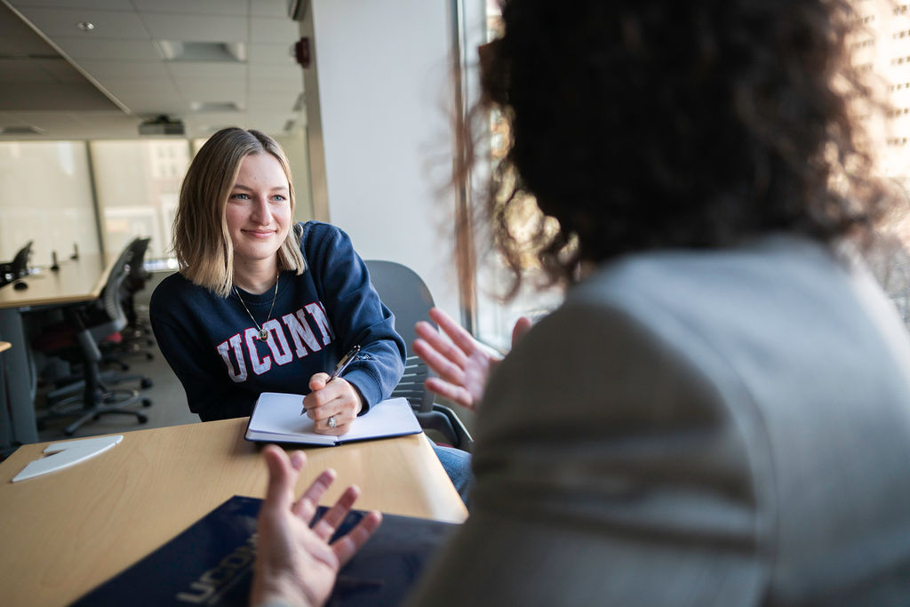 Two women at a table talking. One is a young studenet.